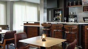 A modern restaurant with a bar area, wooden chairs, and a table with a light fixture. - Courtyard by Marriott St Louis Westport Plaza (Maryland Heights)