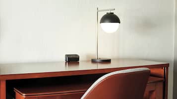 A wooden desk with a black desk lamp and a small black object on it.