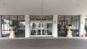 A hotel entrance with glass doors, potted plants, and a paved walkway. - Clarion Hotel Fort Mill Near Amusement Park (Fort Mill)