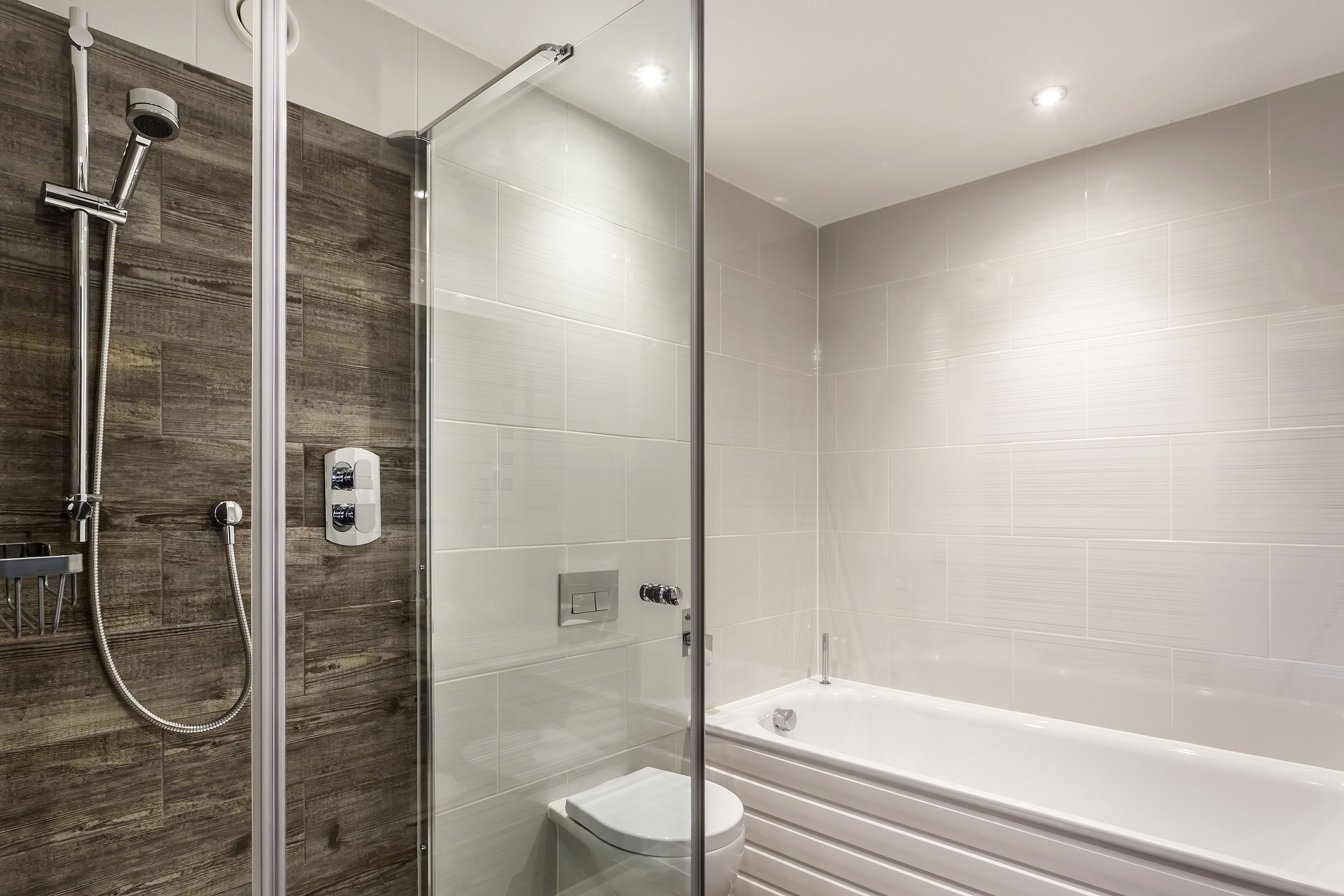 A modern bathroom with a glass-enclosed shower, a white toilet, and a bathtub.