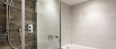A modern bathroom with a glass-enclosed shower, a white toilet, and a bathtub.