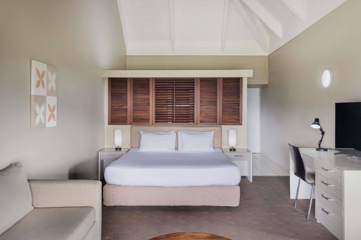 A modern bedroom with a large bed, bedside tables, a desk, and a chair.