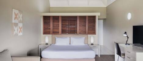 A modern bedroom with a large bed, bedside tables, a desk, and a chair.