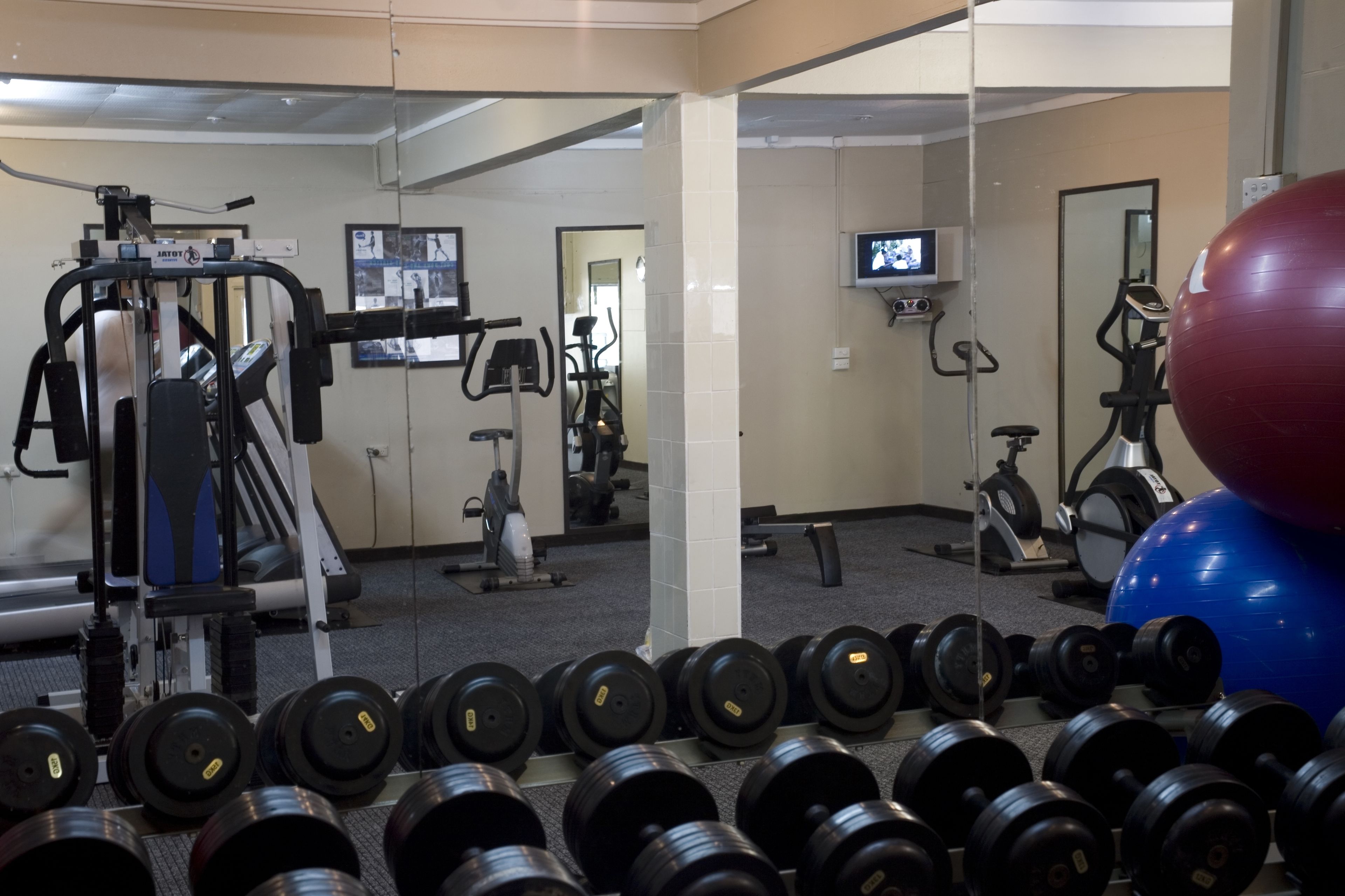 A gym with exercise equipment, a television, and a large exercise ball.