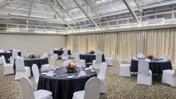 A conference room with round tables, white chairs, and black tablecloths.