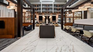 Un hall d’entrée spacieux avec un comptoir d’accueil central, des espaces de détente et un plafond haut doté de lucarnes.