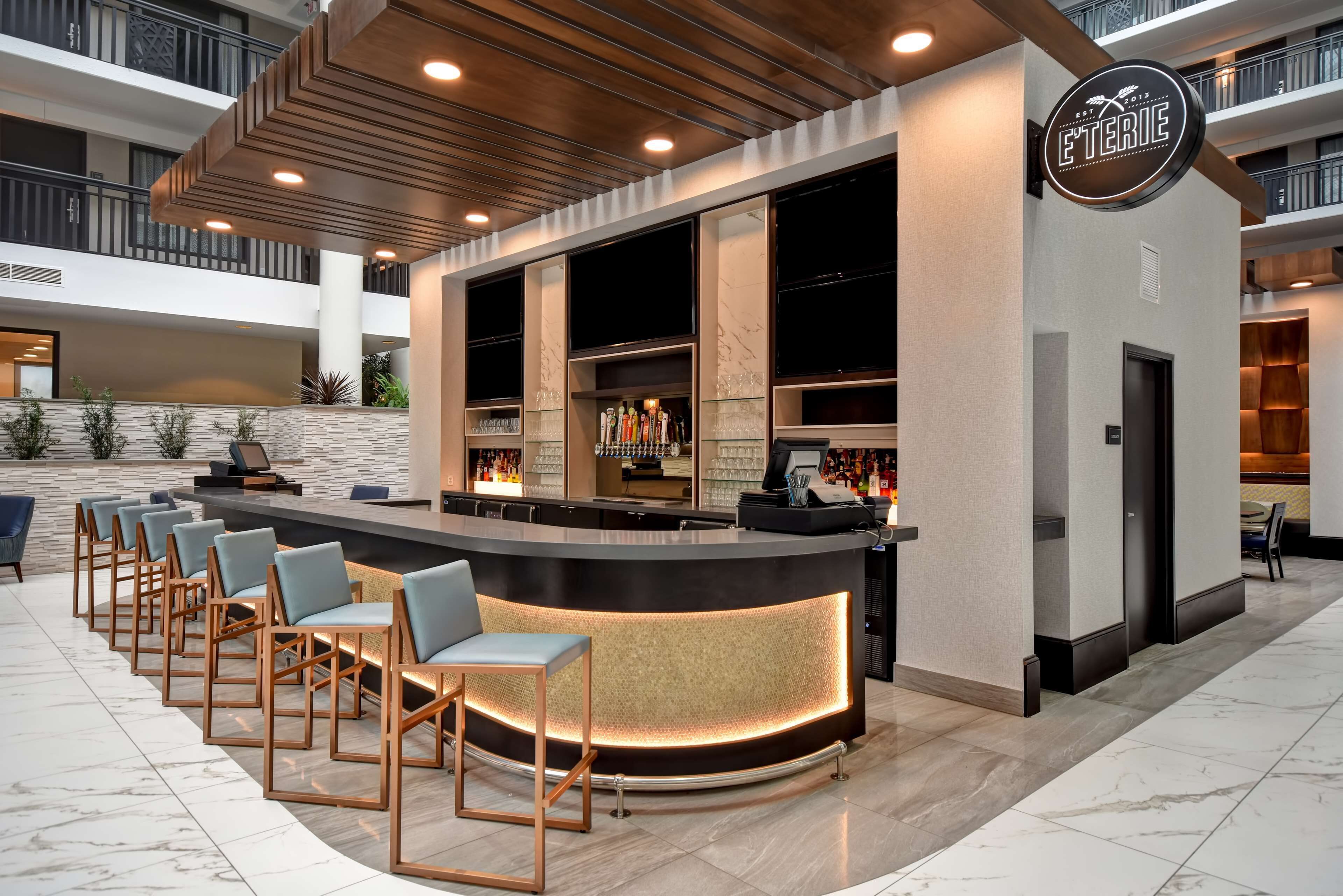 A modern bar area with a curved counter, seating, and a sign reading "L'ETERIE".