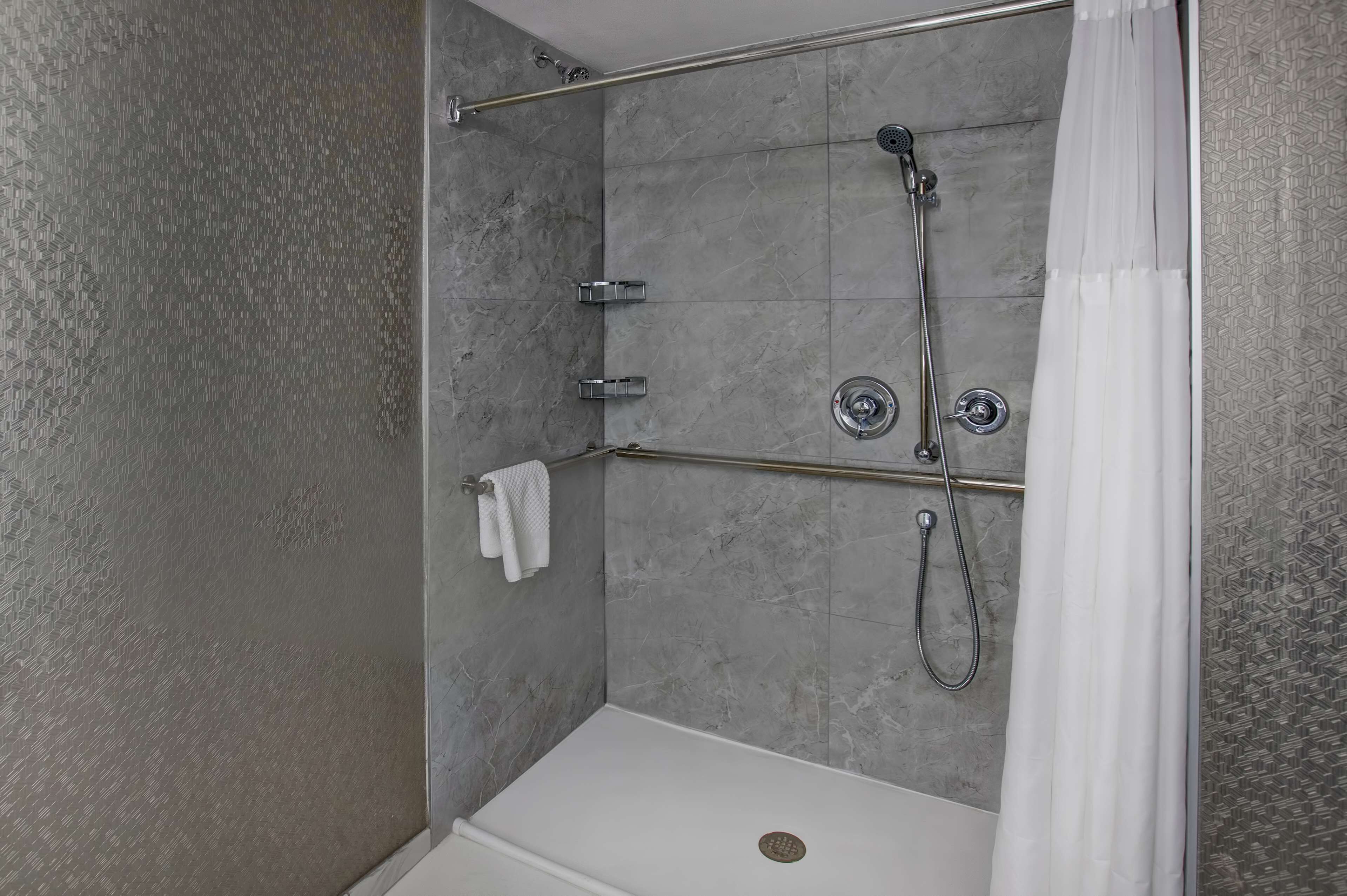 A walk-in shower with a glass door, a towel rack, and a showerhead.