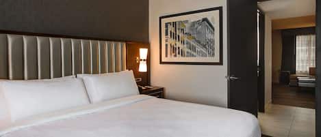 A hotel room with a large bed, a headboard, a nightstand with a lamp, and a framed picture on the wall.