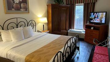 Een hotelkamer met een bed, een televisie, een kledingkast en een raam met gordijnen.