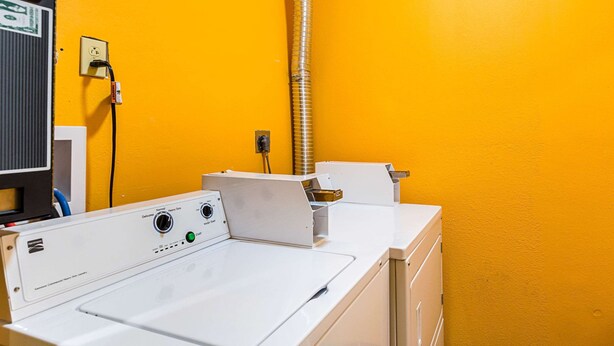 A laundry area with a white washing machine, a dryer, and a yellow wall.