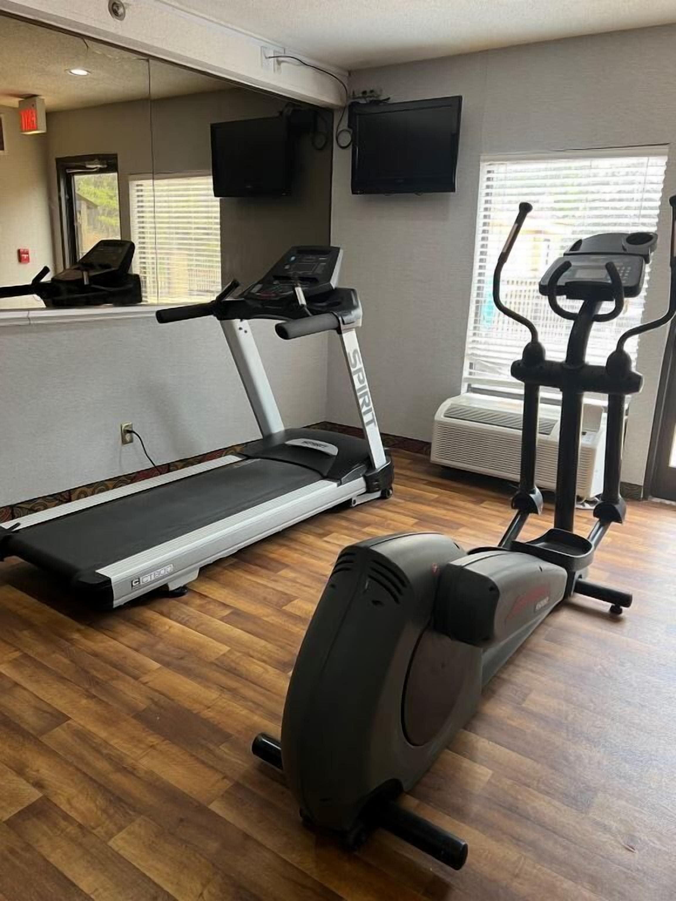 Un gimnasio en casa con cinta de correr, elíptica y bicicleta estática.