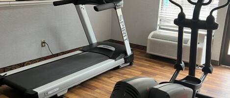 Un gimnasio en casa con cinta de correr, elíptica y bicicleta estática.