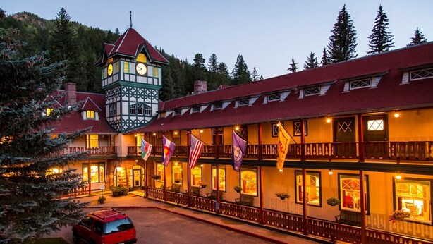 A multi-story hotel with a prominent clock tower, a red roof, and multiple flags.