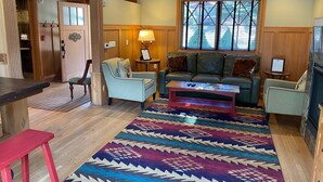 A cozy living room with a sofa, armchairs, a coffee table, and a patterned rug.