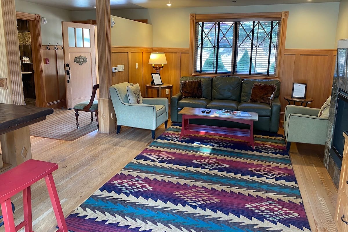 A cozy living room with a sofa, armchairs, a coffee table, and a patterned rug.