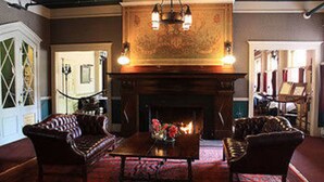 A room with a fireplace, two armchairs, a table, and a patterned carpet.