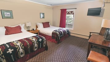 A hotel room with two beds, a TV, a desk, and a chair.