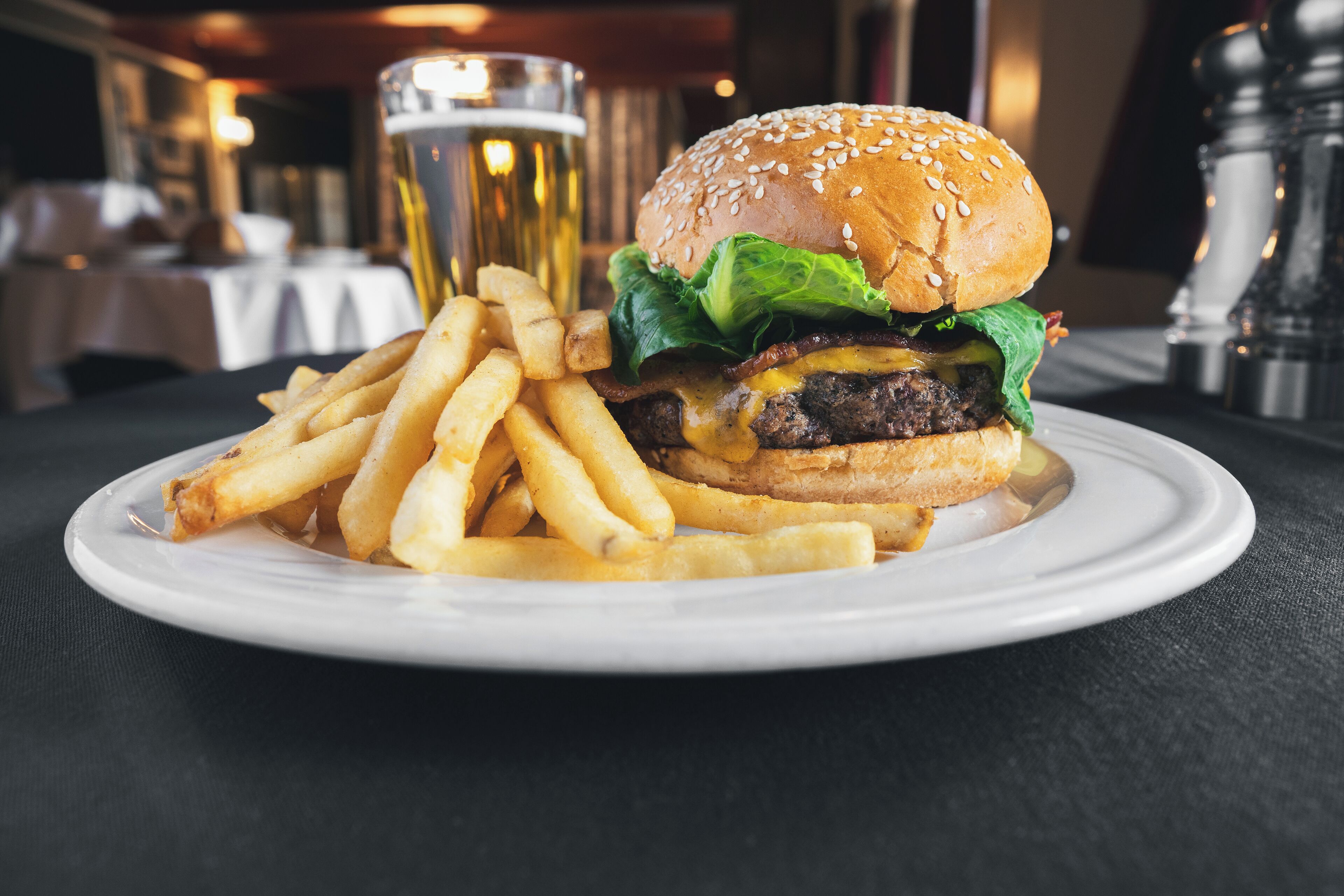 Een bord met een hamburger en frieten op een tafel in een restaurant.
