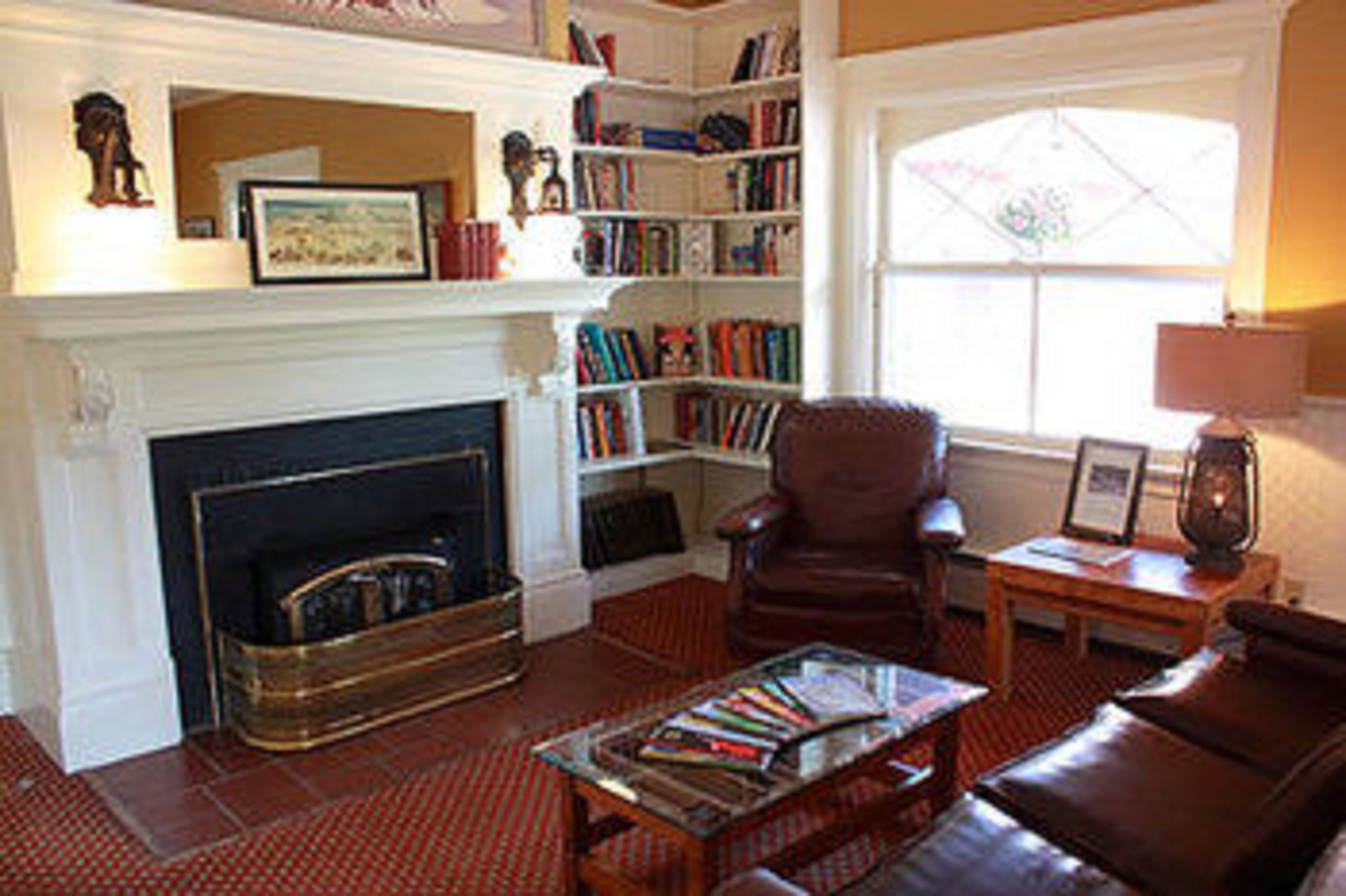 A living room with a fireplace, bookshelves, a leather armchair, and a coffee table.