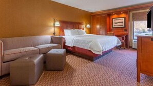 A hotel room with a bed, a sofa, a desk, and a chair. - Par-A-Dice Inn (East Peoria)