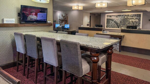A hotel lobby with a reception desk, a television mounted on the wall, and a dining area with a table and chairs. - Par-A-Dice Inn (East Peoria)