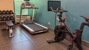 A gym with a treadmill, stationary bike, dumbbells, and a bench. - Par-A-Dice Inn (East Peoria)