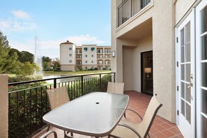 Enjoy the garden view from this balcony with a table and chairs.