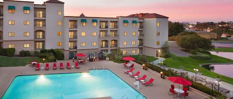 Een buitenzwembad, parasols bij het zwembad en ligstoelen