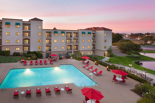 Relax by the pool surrounded by comfortable lounge chairs and umbrellas, with a beautiful view of the adjacent water.