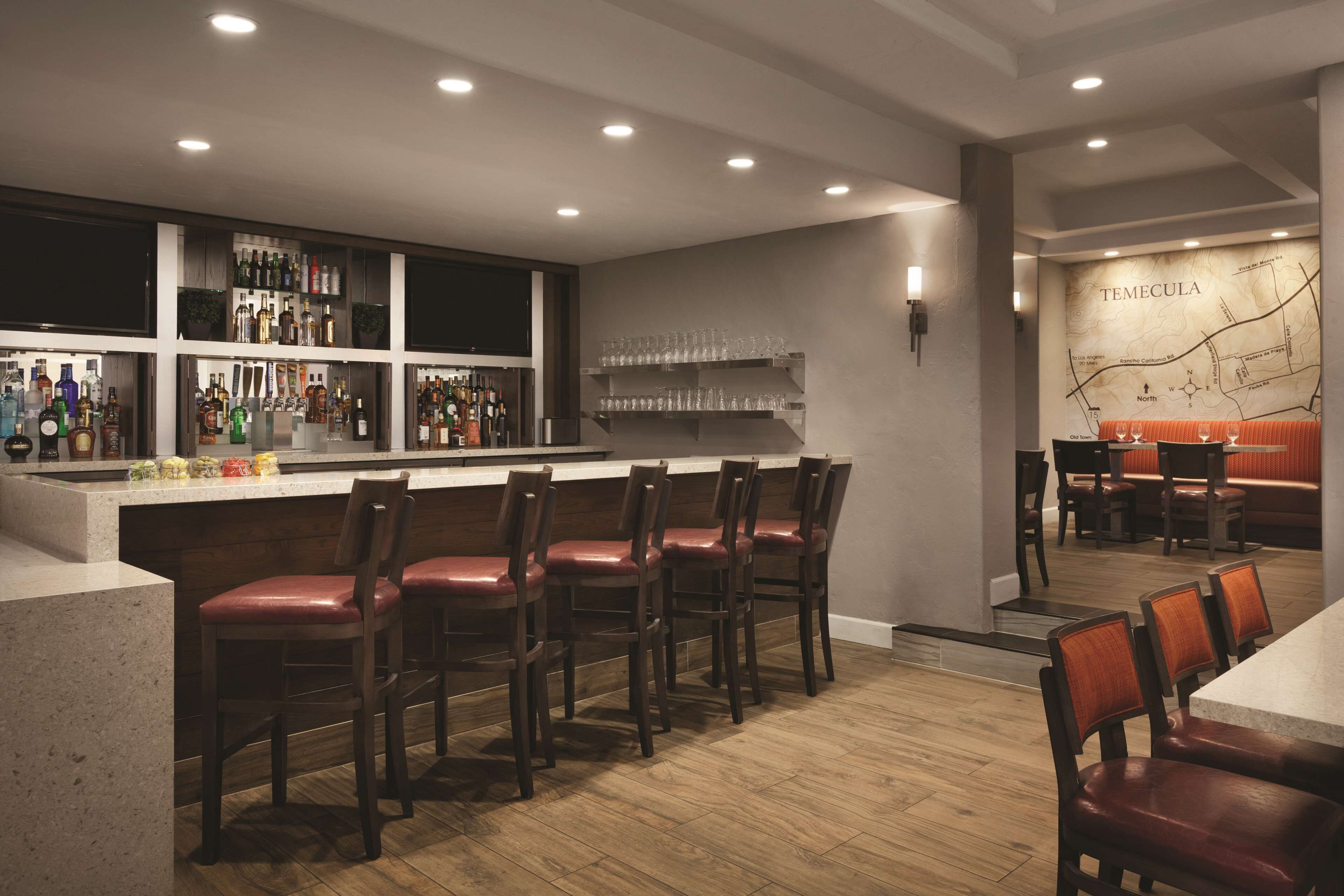 A bar area with wooden bar stools, a countertop with bottles, and a wall map labeled "TEMECULA".