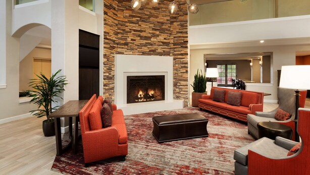 A spacious living area with a fireplace, modern furniture, and a stone accent wall. - Embassy Suites by Hilton Temecula Valley Wine Country (Temecula)