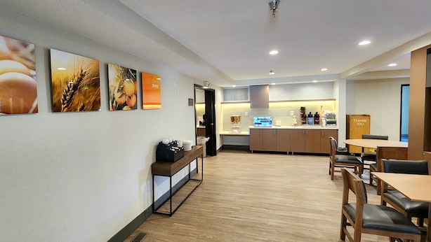 Um restaurante moderno com piso de madeira, um balcão com cardápio e uma parede com quadros emoldurados.