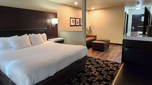 Quarto de hotel com cama grande, escrivaninha, cadeira, mesa pequena e televisão.