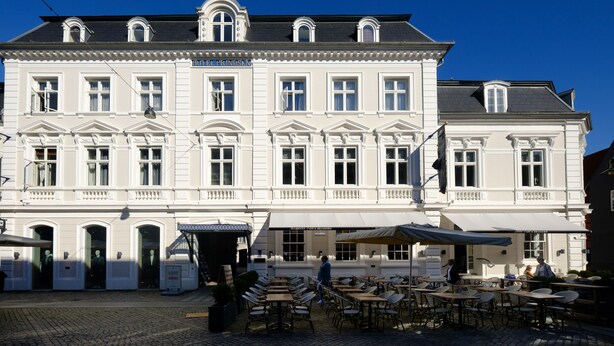A historic building with a cafe on the ground floor, featuring outdoor seating and a cobblestone street. - Four Points Flex by Sheraton Roskilde (Roskilde)