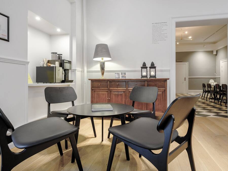 A modern dining area with a round table, four chairs, a lamp, and a wooden cabinet with decorative items.