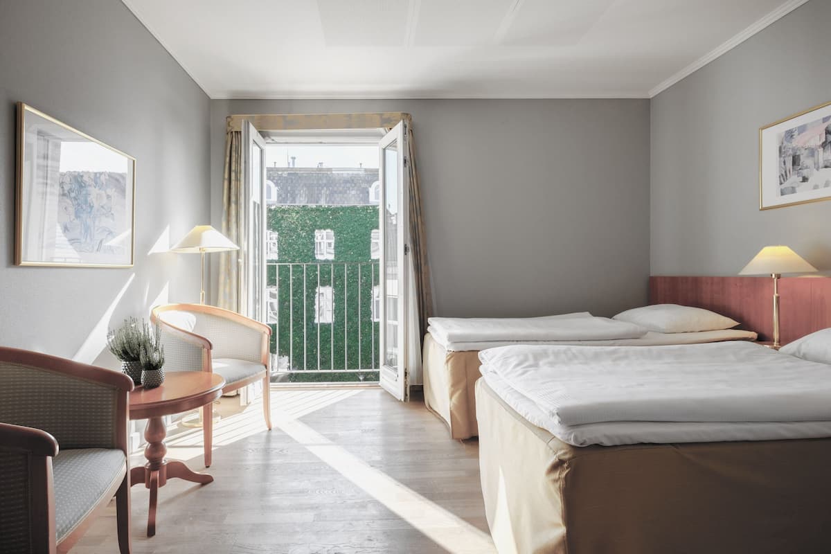 Habitación de hotel con cama, una silla, un escritorio y vistas al exterior.
