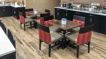 Un espace repas avec des tables et des chaises, une poubelle et une machine à café.