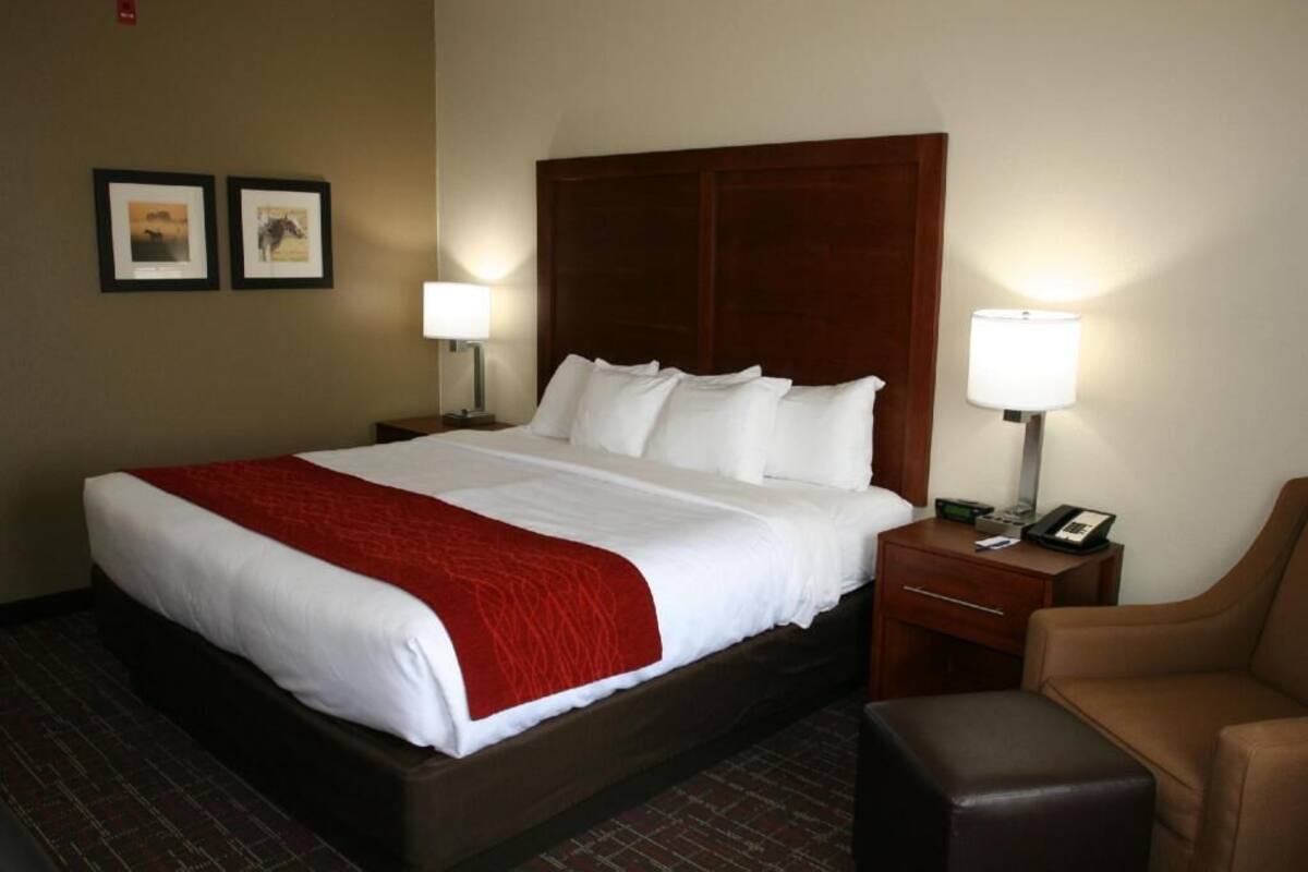 A hotel room with a large bed, two bedside tables with lamps, a chair, and a small table.