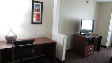 Habitación de hotel con escritorio, silla, televisión y un cuadro en la pared.
