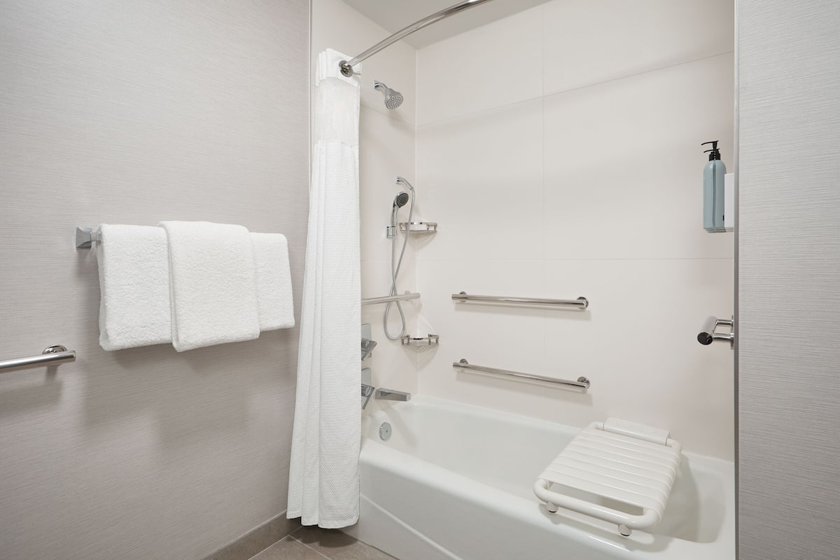 Ein modernes Badezimmer mit Badewanne, Dusche und Haltegriffen.