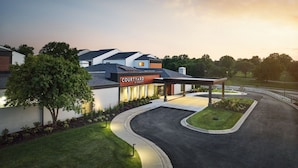 A Courtyard by Marriott hotel with a modern design, featuring a curved driveway and well-maintained landscaping. - Courtyard by Marriott Kansas City Overland Park/Metcalf (Overland Park)