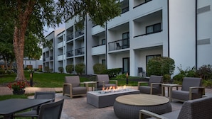 An outdoor patio with seating, a fire feature, and a building in the background. - Courtyard by Marriott Kansas City Overland Park/Metcalf (Overland Park)