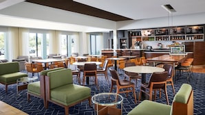 A modern hotel lobby with multiple seating areas, a bar, and a visible outdoor view. - Courtyard by Marriott Kansas City Overland Park/Metcalf (Overland Park)