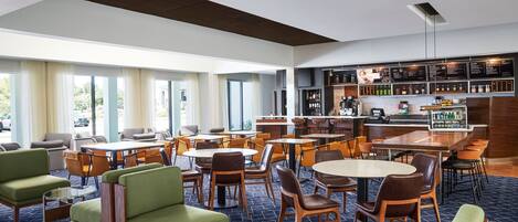 Un moderno vestíbulo de hotel con varias zonas de estar, un bar y vistas al exterior.