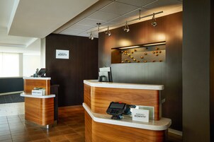 A reception area with two wooden reception desks, each with a nameplate, a phone, and a digital display.