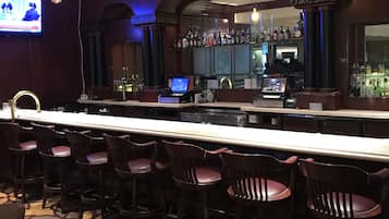 Un'area bar con un lungo bancone, diversi sgabelli da bar e illuminazione a sospensione.