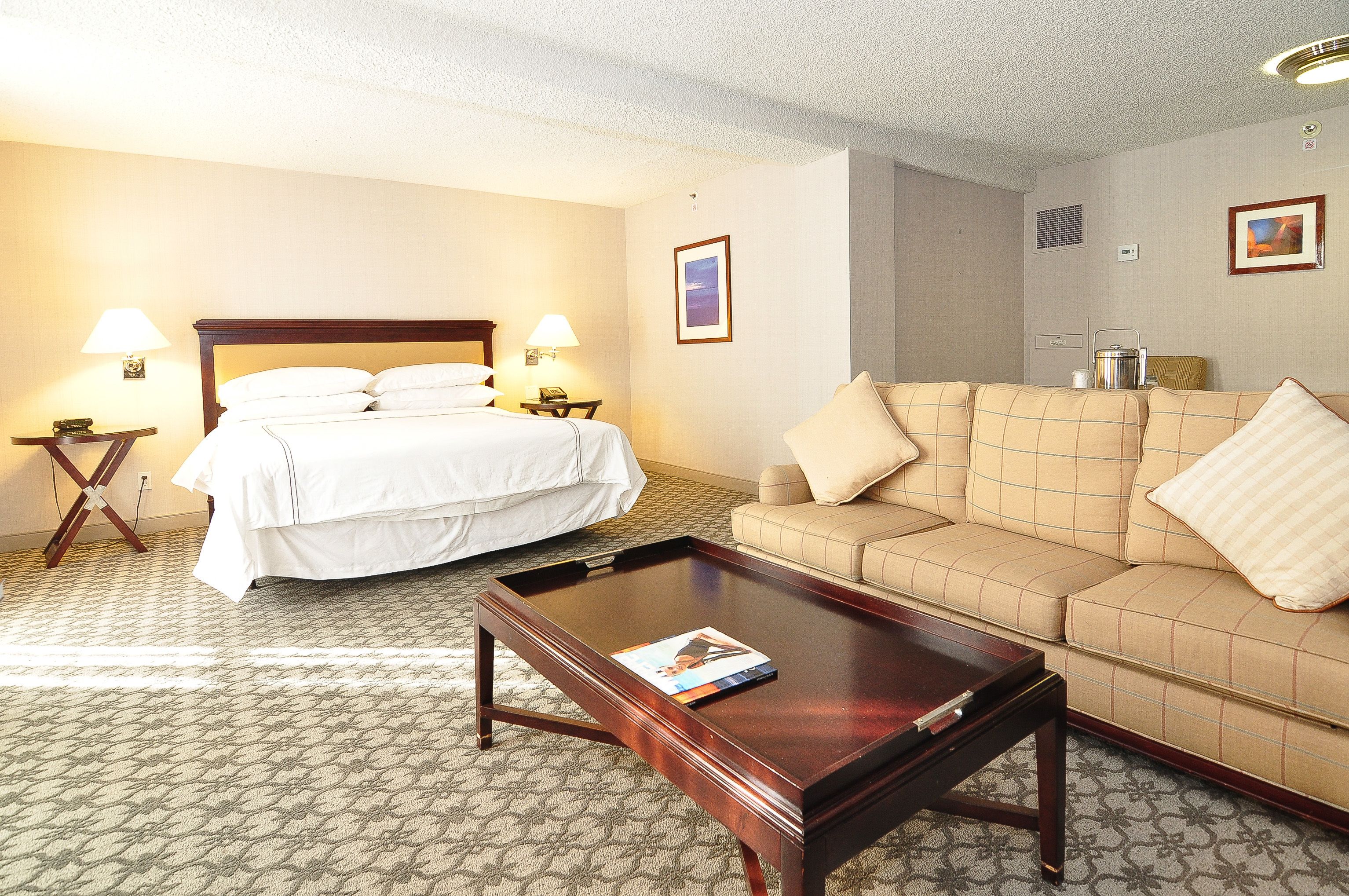 A hotel room with a bed, a sofa, a coffee table, and two lamps.