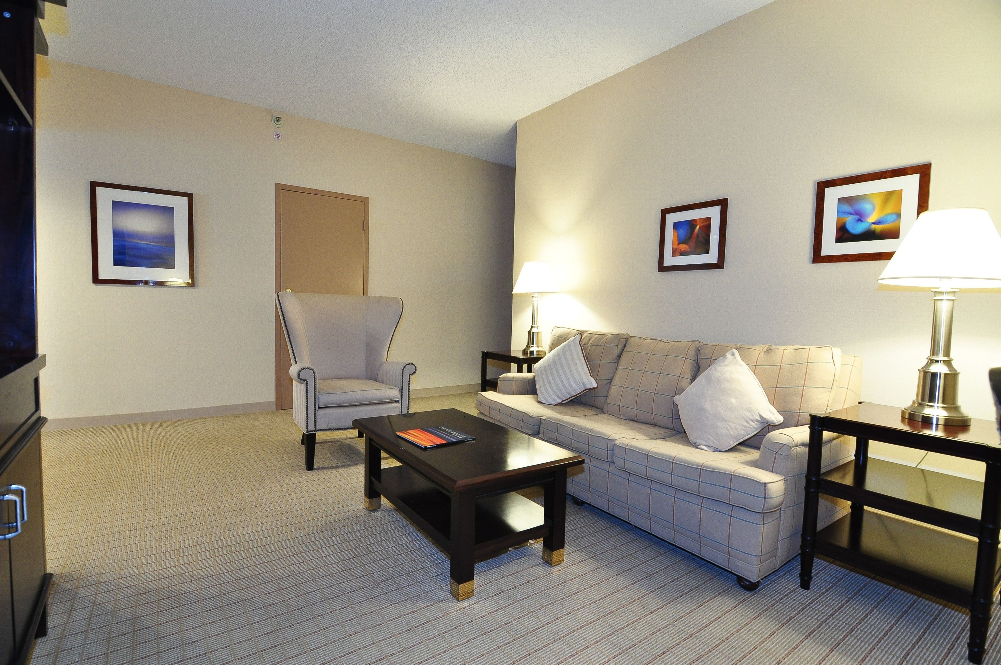 Une chambre d’hôtel équipée d’un canapé, d’un fauteuil, d’une table basse et d’un téléviseur.
