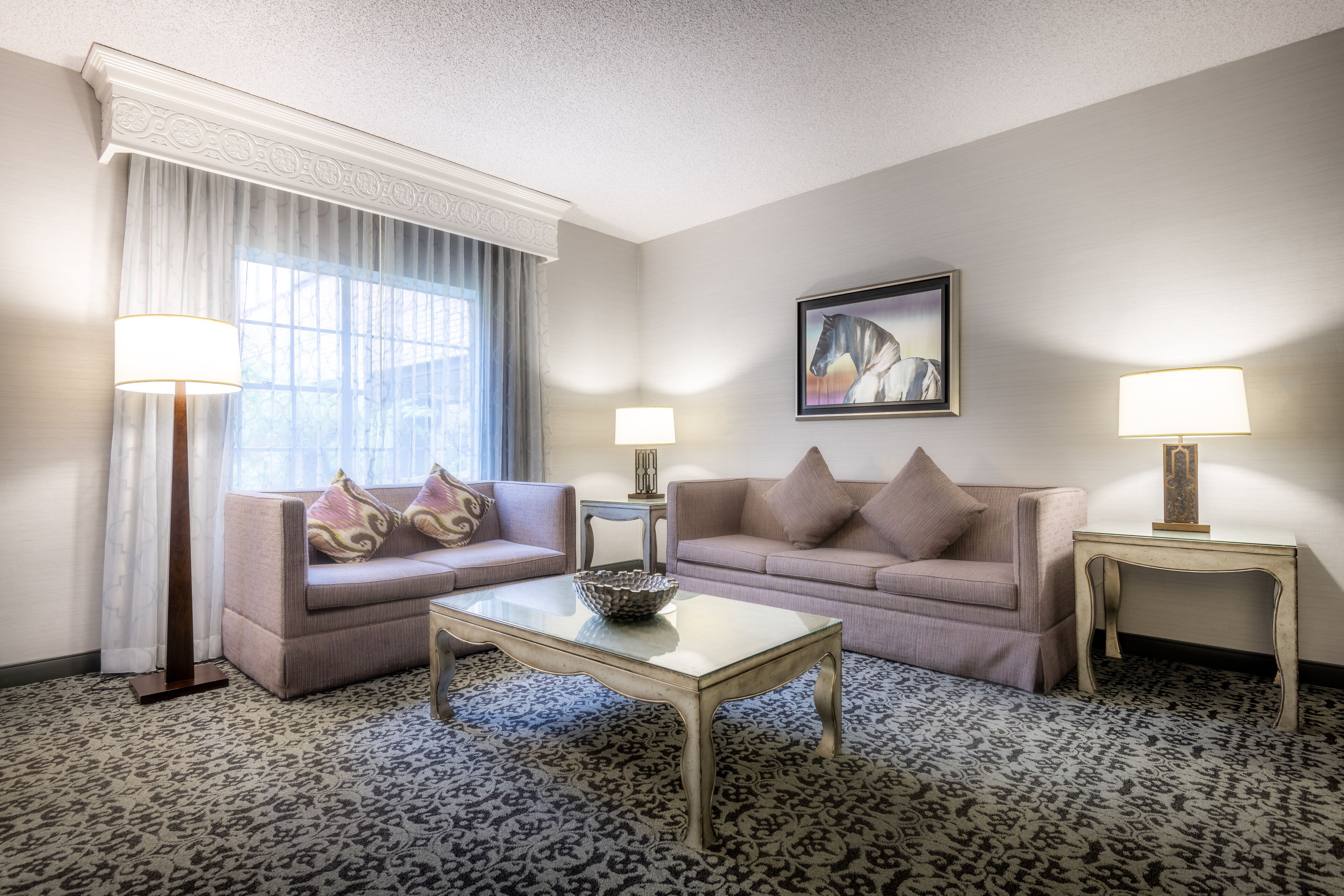 A hotel room with two sofas, a coffee table, and two lamps.